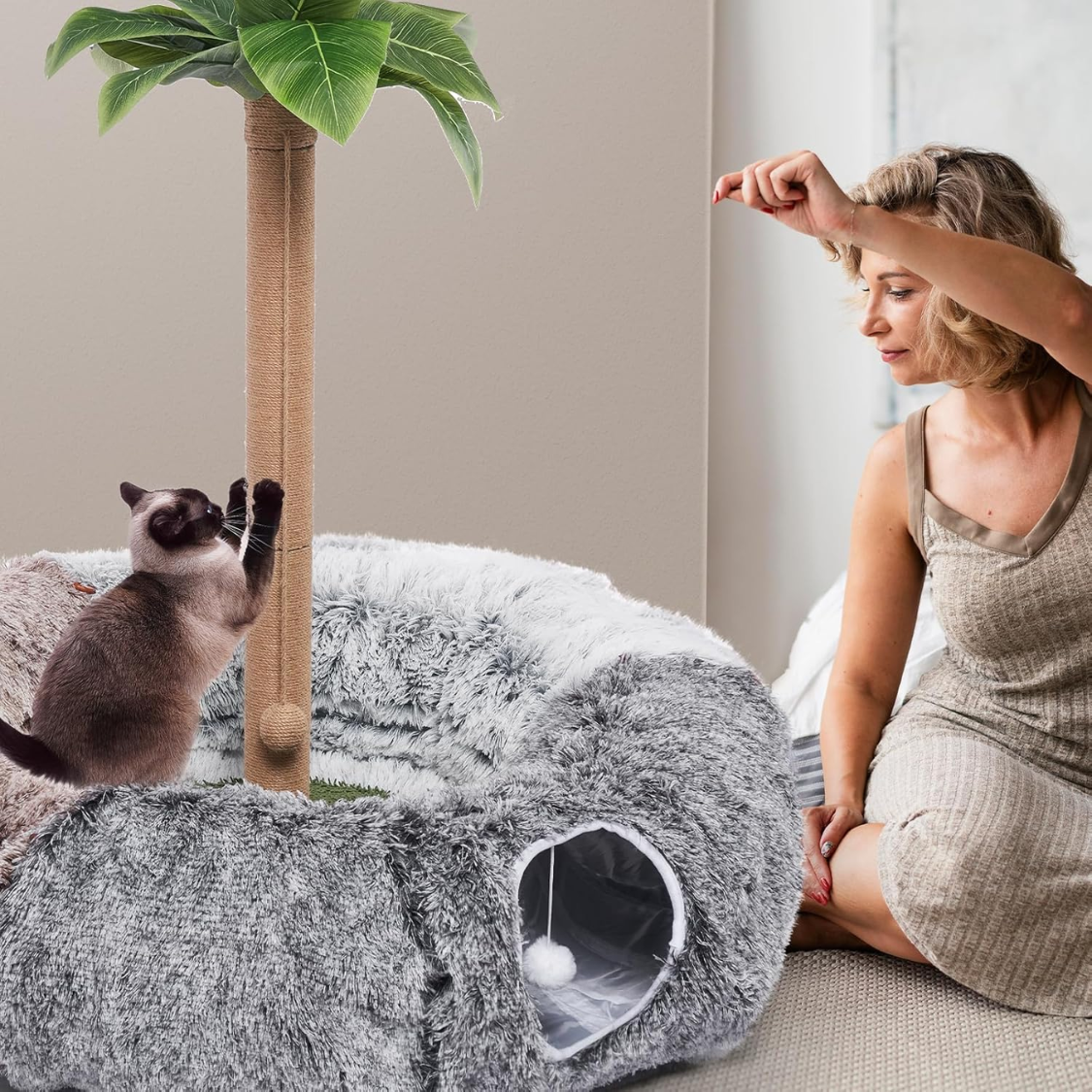 Woman sitting beside a fluffy donut cat tunnel with her cat
