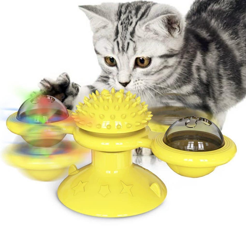Silver tabby kitten batting the spinning yellow windmill cat toy with star-embossed suction base, spiky massage ball, and colorful ball domes in motion.
