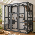 Large grey wooden outdoor cat enclosure with wire mesh panels and shelves, with several cats resting inside a bright sunroom