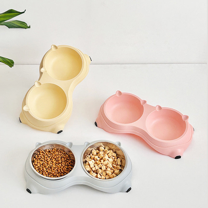 Three macaron stainless steel pet bowls in yellow, pink and white, one filled with dry food and treats