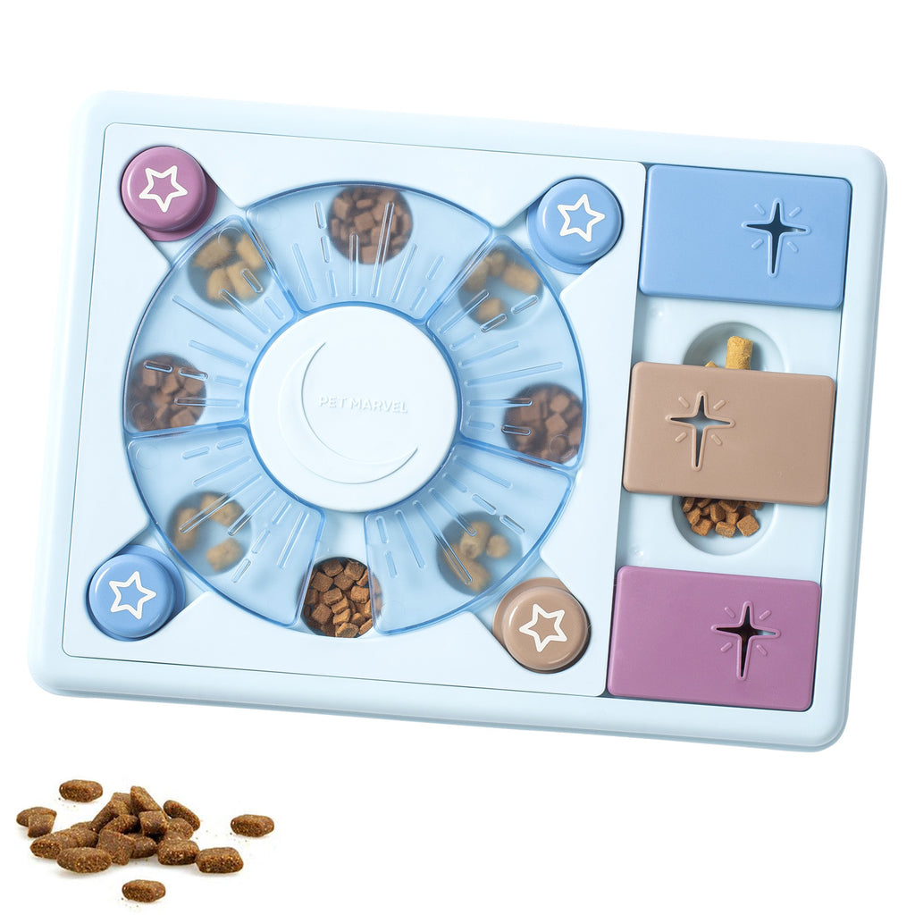 Overhead view of the square light-blue puzzle board with a circular kibble spinner, pastel sliding tiles, star-shaped buttons, and kibble scattered beside it.