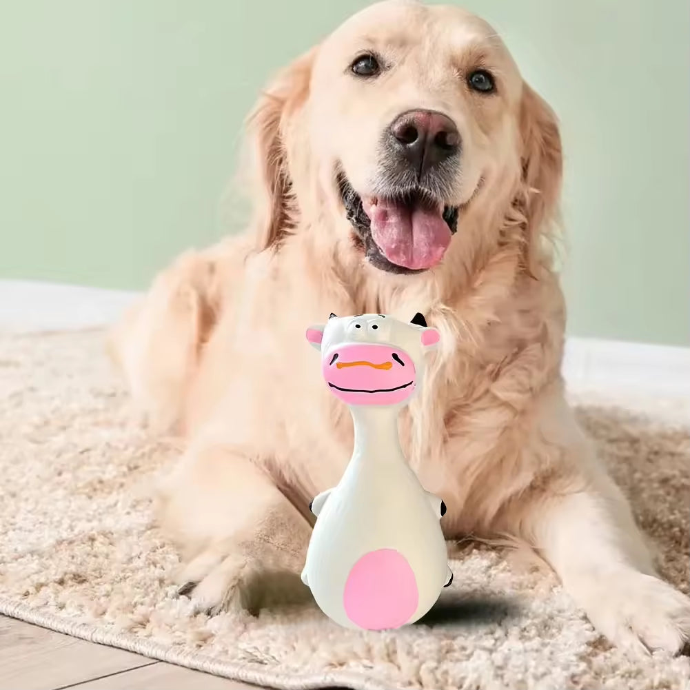 Golden Retriever lying on a rug smiling behind a white and pink latex cow-shaped squeaky chew toy.
