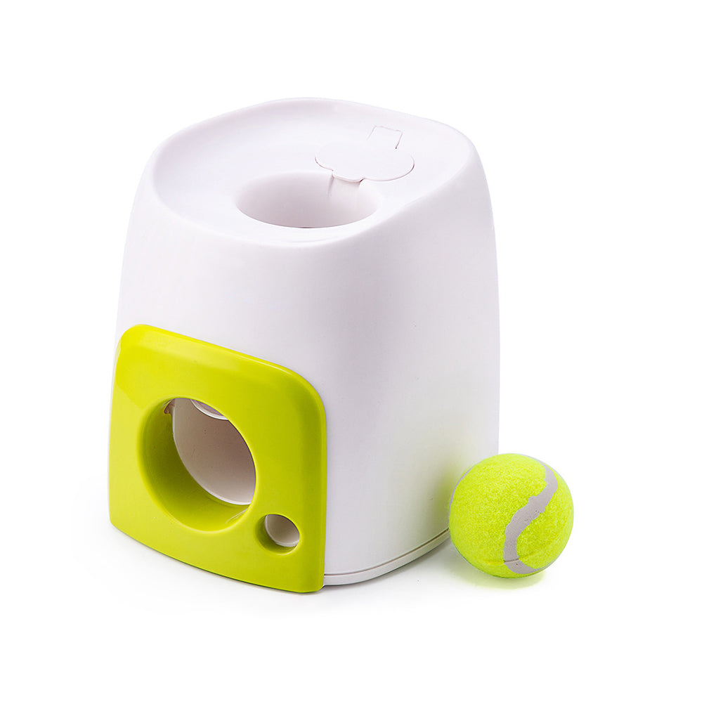 White dog ball reward machine with lime-green front panel and ball-dispensing slot, with a tennis ball beside it on a white background.