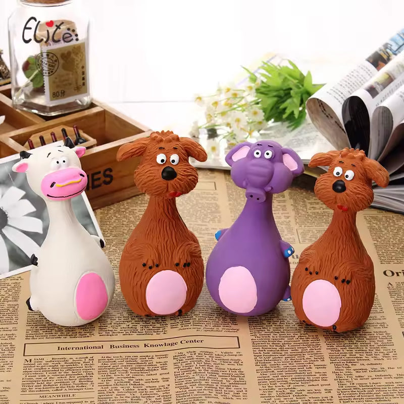 Four latex animal squeaky dog toys lined up on newspaper: white cow, brown dog, purple elephant, and brown dog, each with a pink belly.