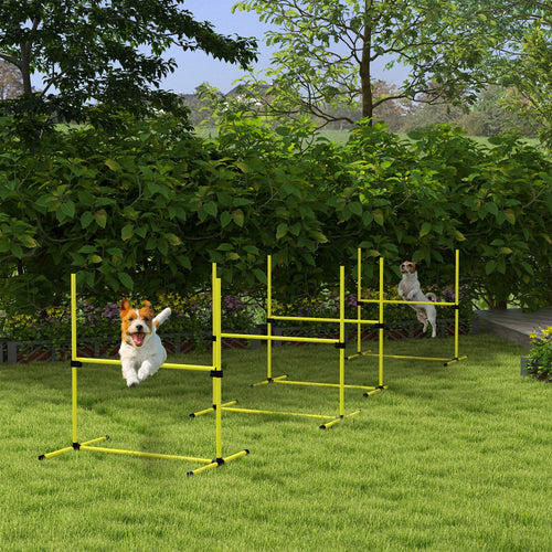 Two dogs jumping through yellow agility jump bars on green grass