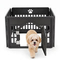 Black modular plastic dog playpen with paw print cutout and locking door; small fluffy cream dog walking out of the portable pet fence